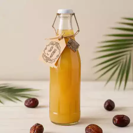 Pure organic date syrup produced from EcoDateFarm's premium Medjool dates in Jaisalmer, Rajasthan, showing thick golden liquid in glass bottle